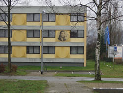 Der neue Zugang zur Gedenkstätte vom Hotelparkplatz aus; auf der Fassadenverkleidung des "Novotel" wurde stellvertretend für alle weiblichen Häftlinge das Portait von Yvonne Bermann angebracht. Foto: Claudia Maas, 2004